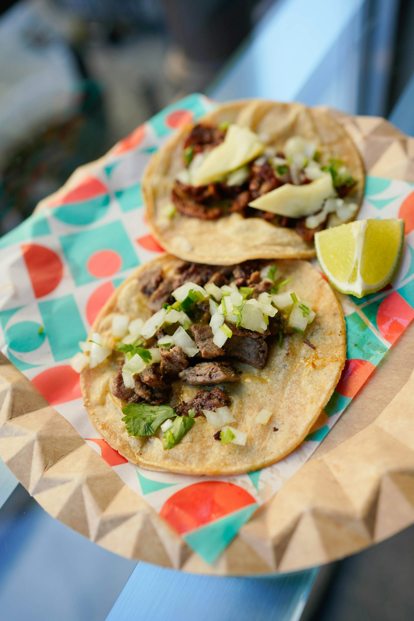 Tacos de pastor y asada servidos sobre papel estampado, imagen representativa